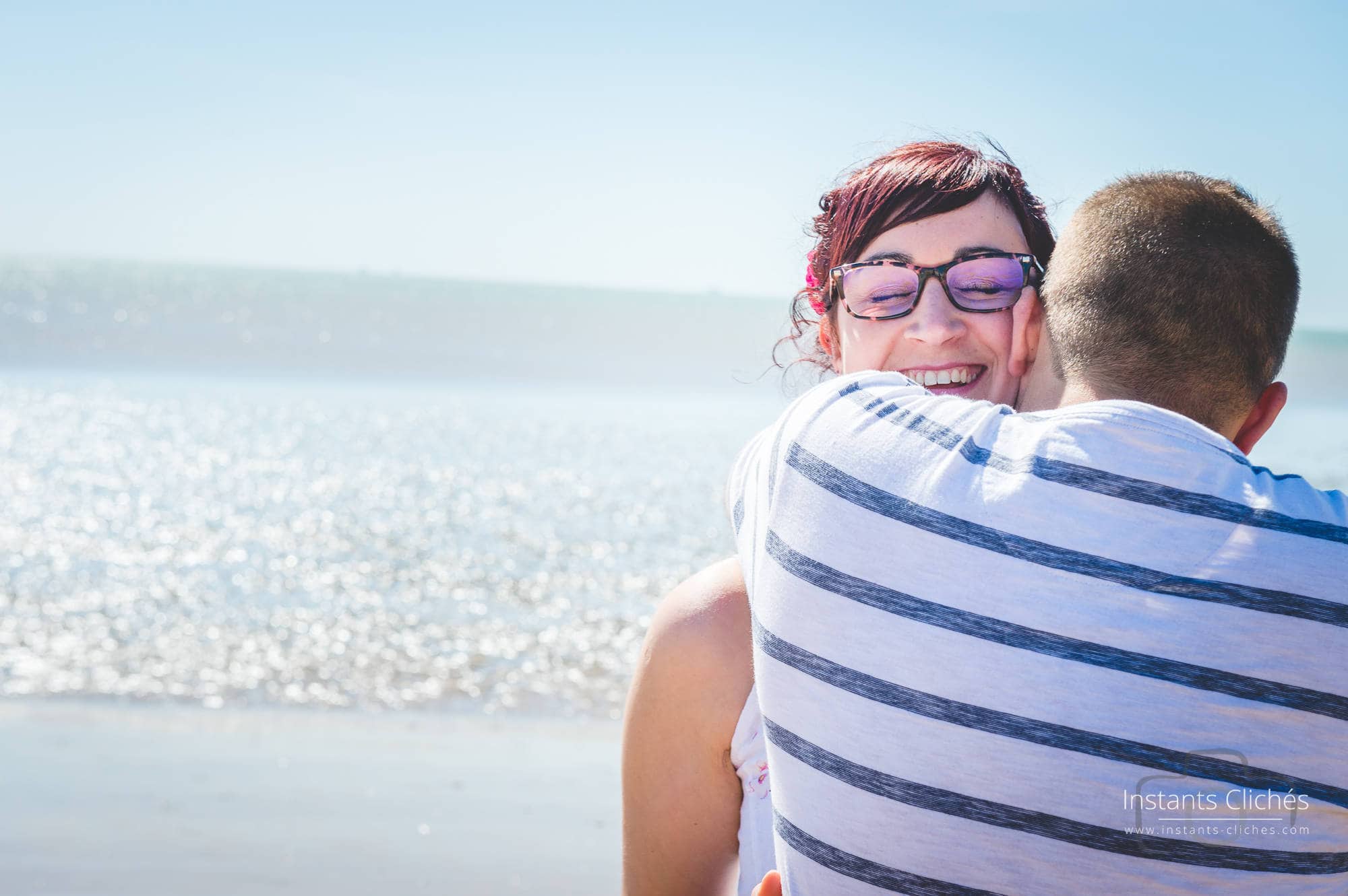 Couple souriant sur la plage de Chatelaillon avec mer en arrière-plan.