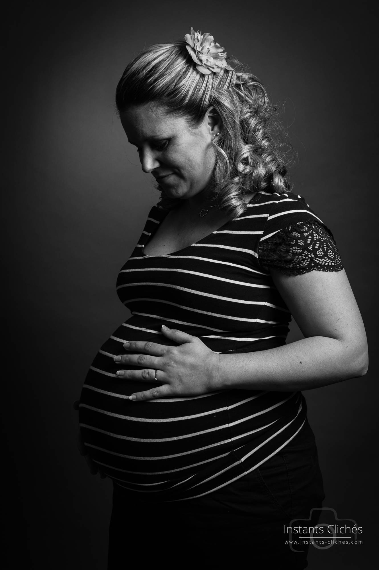 Femme enceinte en portrait noir et blanc, regardant son ventre.