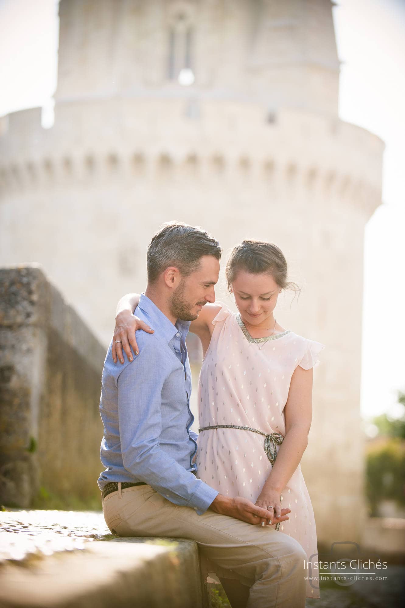 Jeune couple romantique devant un château historique en plein air.