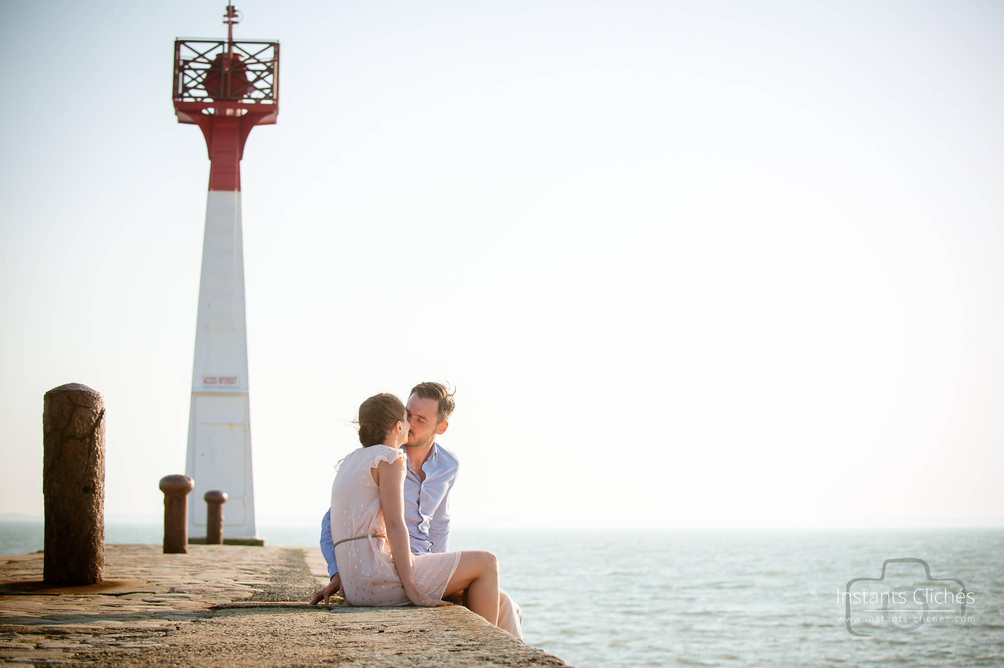 Jeune couple assis près du phare de Chatelaillon-Plage au coucher du soleil.